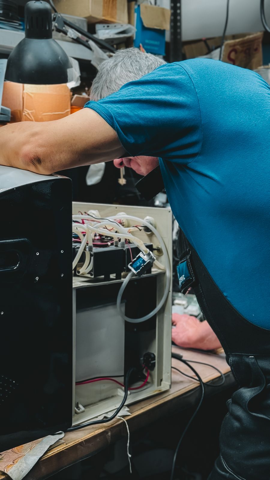 A workshop technician inspecting equipment on a repair bench